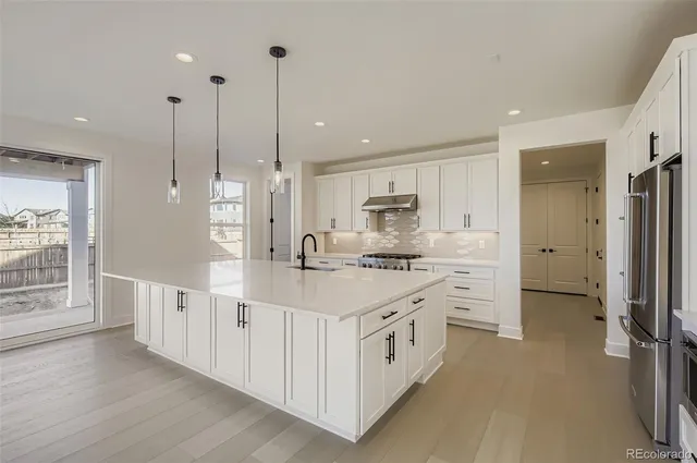 a kitchen with stainless steel appliances kitchen island granite countertop a stove a sink and a refrigerator with wooden floor