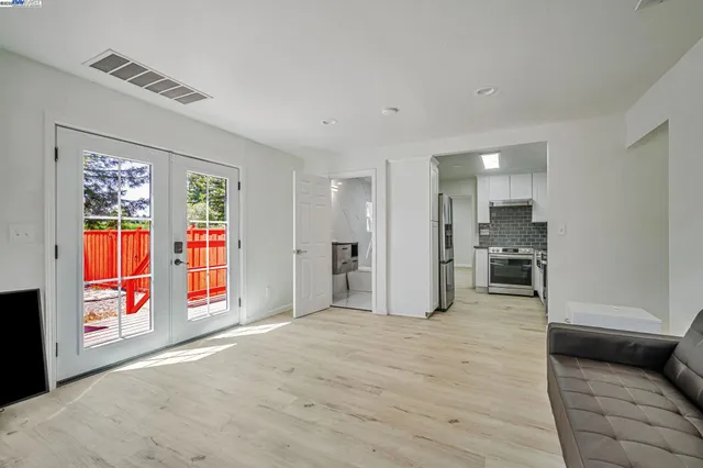 a view of an empty room with window and kitchen view
