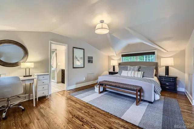 a spacious bedroom with a bed a dresser and wooden floor