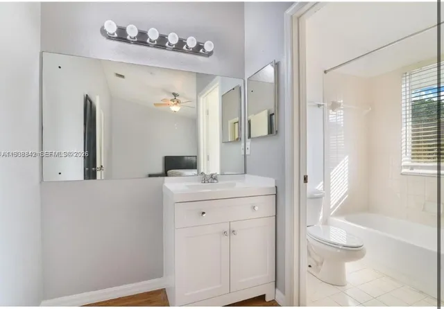 a spacious bathroom with a granite countertop sink a toilet a mirror and shower