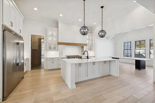 a kitchen with stainless steel appliances granite countertop a refrigerator a stove and a sink with wooden floor