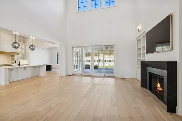a large white kitchen with a large window stainless steel appliances and a chandelier