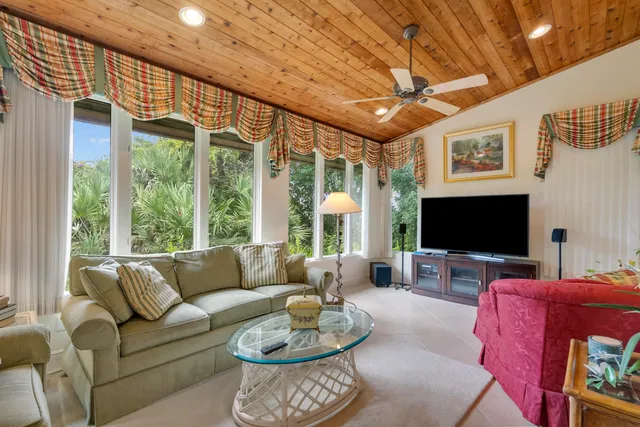 a living room with furniture a flat screen tv and floor to ceiling window