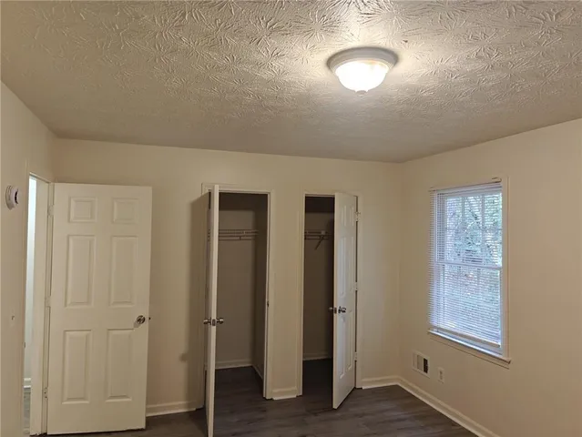 an empty room with wooden floor closet and windows