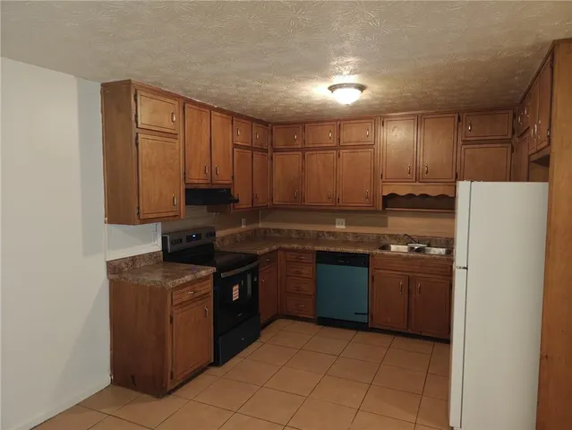 a kitchen with stainless steel appliances granite countertop a stove a refrigerator and a sink with wooden cabinets