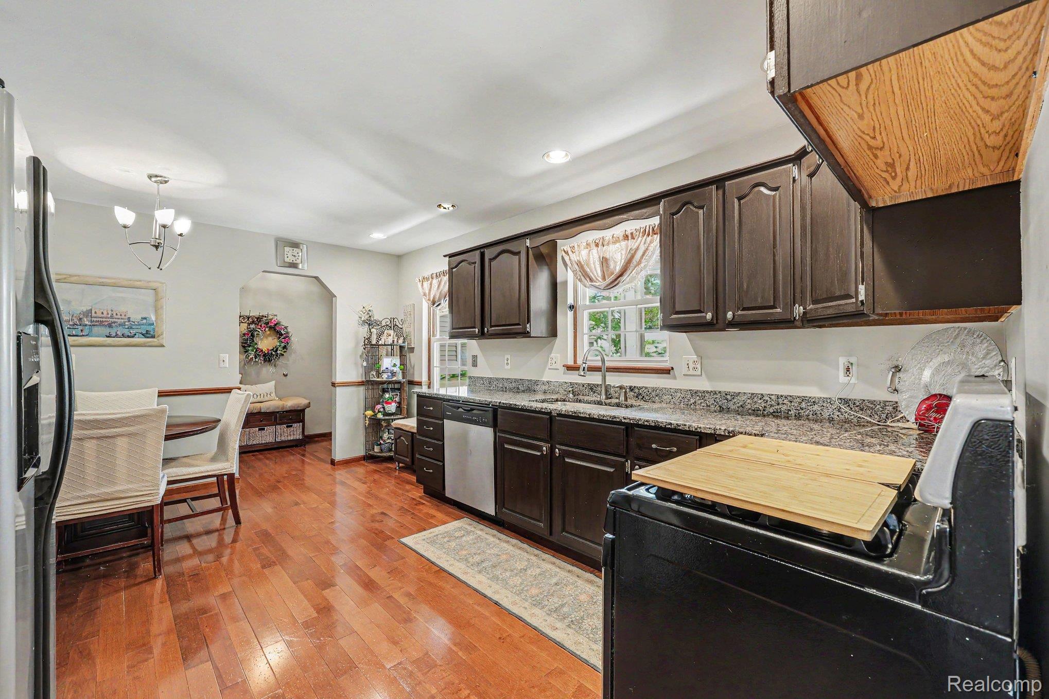 7020 Meldrum Road Fair Haven, MI 48023 - Photo 14 of 43 Kitchen featuring wood-finish flooring, dark wood cabinetry, and granite countertops