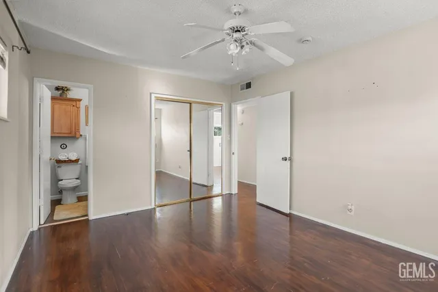 a view of an empty room with wooden floor and a ceiling fan