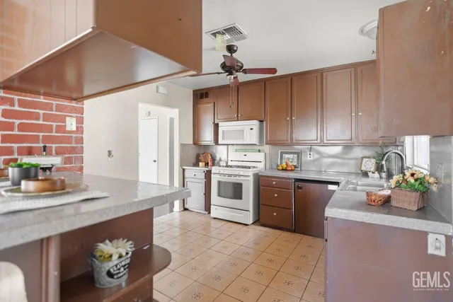 a kitchen with stainless steel appliances a sink a stove a refrigerator cabinets and a window