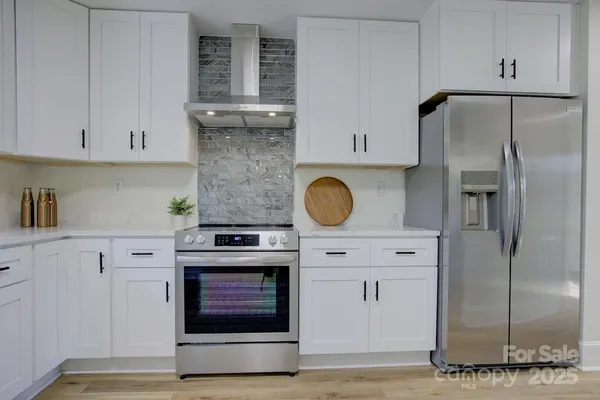 a kitchen with stainless steel appliances granite countertop a stove and a refrigerator with white cabinets