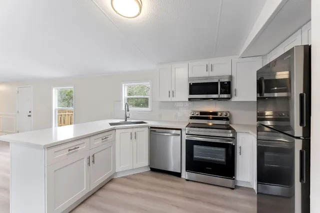 a kitchen with white cabinets stainless steel appliances and sink