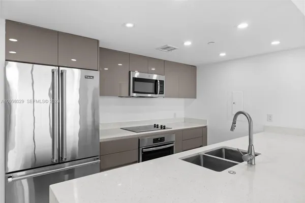a large kitchen with a large counter top space a sink stainless steel appliances and cabinets