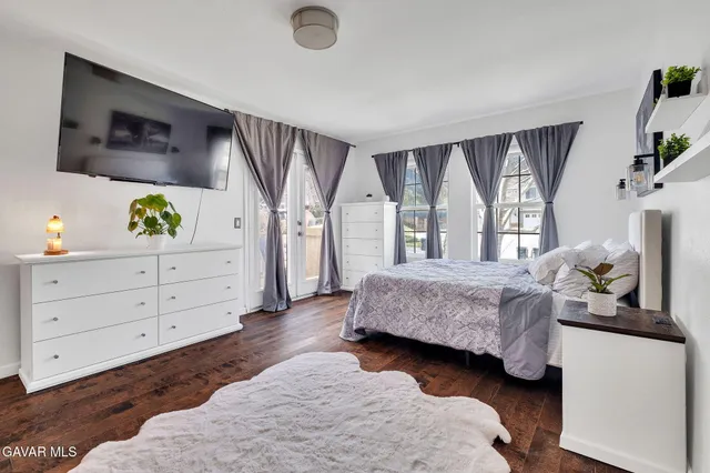 a spacious bedroom with a bed table flat screen tv and a window