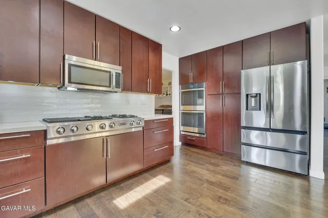 a kitchen with stainless steel appliances wooden cabinets and wooden floor