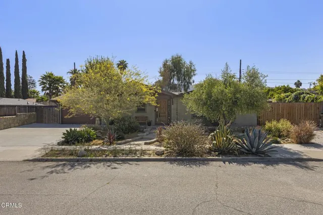 a pathway of a house and cars parked on road