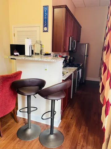 a kitchen with stainless steel appliances a dining table chairs and a wooden floor