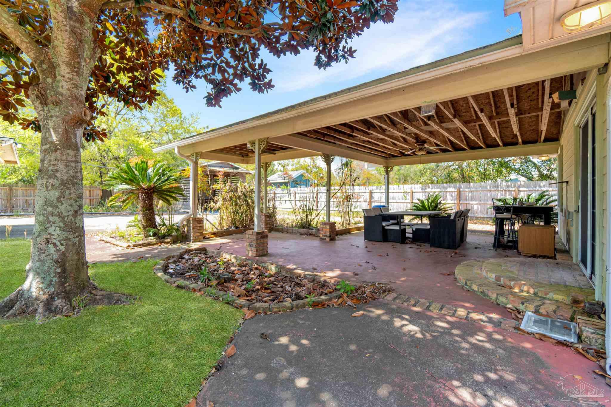 1961 Guseman Road Gulf Breeze, FL 32563 - Photo 27 of 37 a view of a patio with table and chairs under an umbrella with large trees