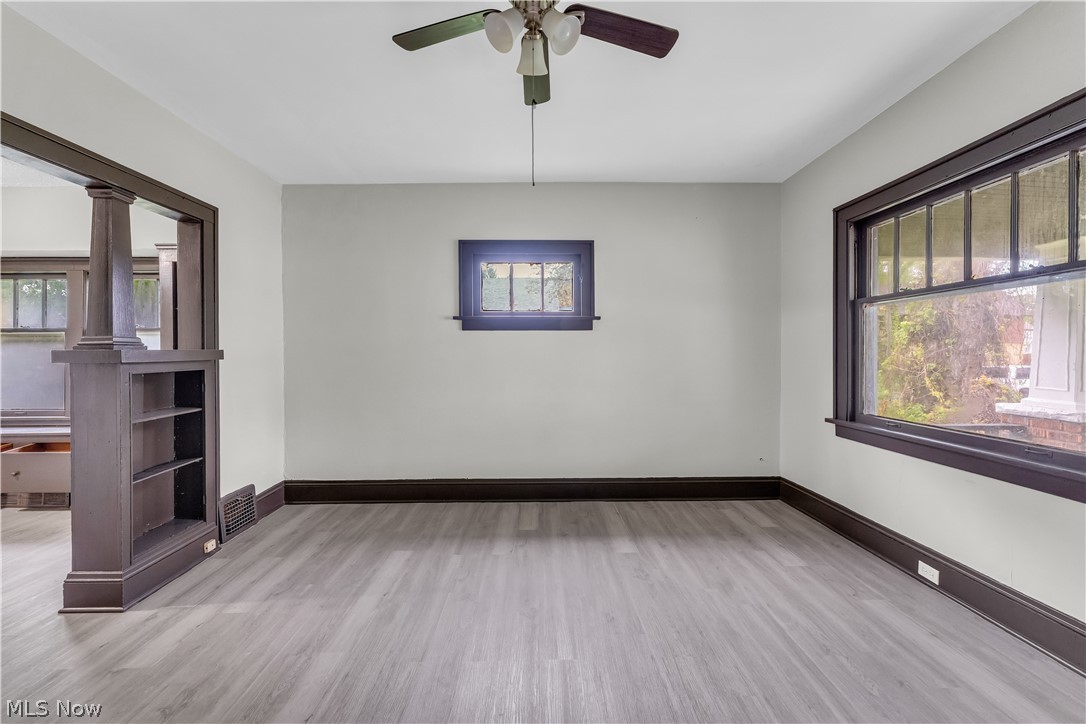 1144 East 145th Street, Unit 1/RIGHT Cleveland, OH 44110 - Photo 5 of 20 Light gray wood-finish flooring complemented by dark trim, large casement windows, a built-in bookshelf, and a ceiling fan