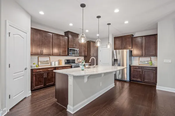 a kitchen with kitchen island granite countertop stainless steel appliances and wooden cabinets