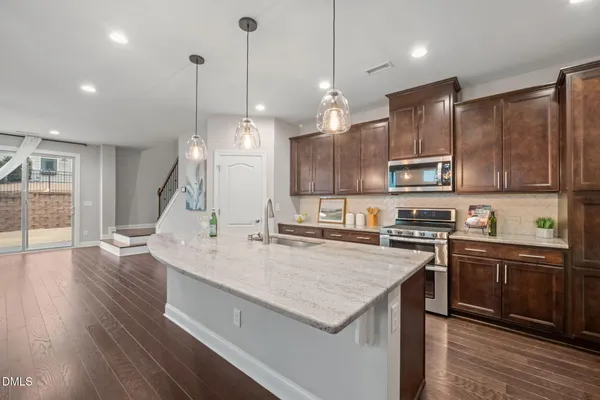 a kitchen with kitchen island granite countertop a sink a counter space appliances and cabinets