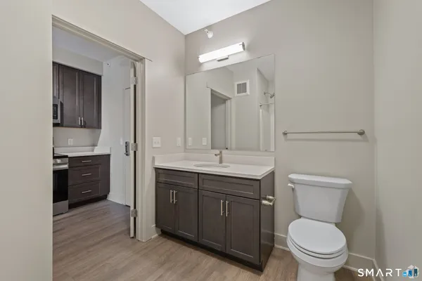 a bathroom with a granite countertop toilet a sink and a mirror