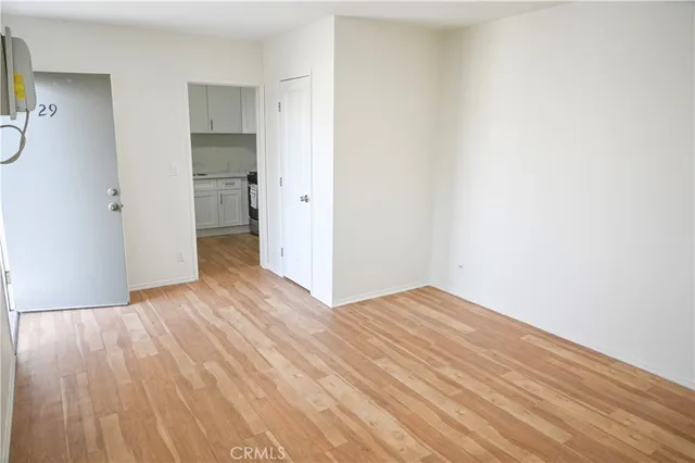a view of an empty room with wooden floor and a bathroom