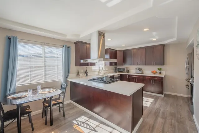 a kitchen with a table chairs a sink dishwasher a stove and cabinets with wooden floor