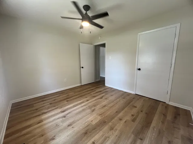 an empty room with wooden floor and a ceiling fan