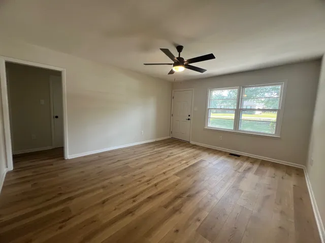 an empty room with wooden floor and windows