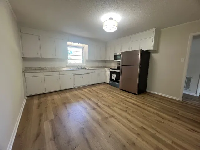 a kitchen with a refrigerator and wooden floor