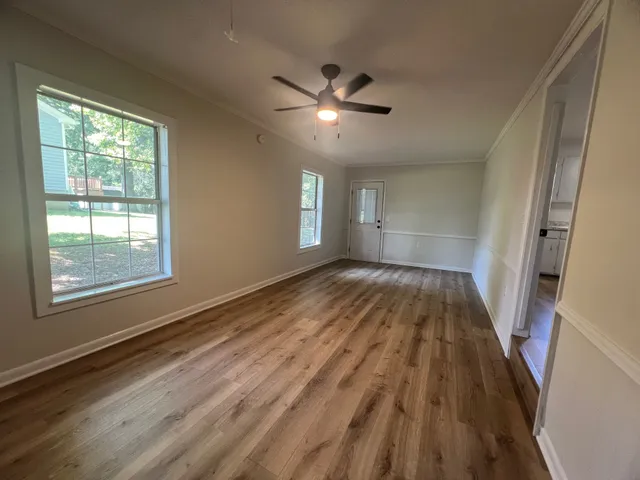 a view of empty room with wooden floor and fan