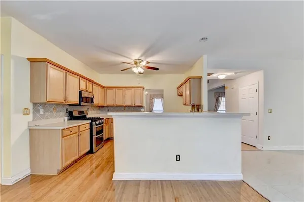 a kitchen with stainless steel appliances a stove top oven a sink a refrigerator white cabinets and wooden floor