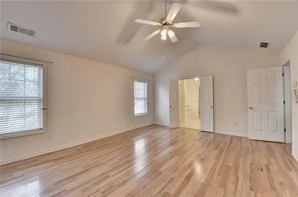 an empty room with wooden floor fan and windows