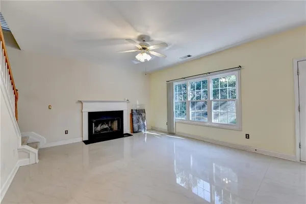 a view of livingroom with a fireplace a ceiling fan and windows