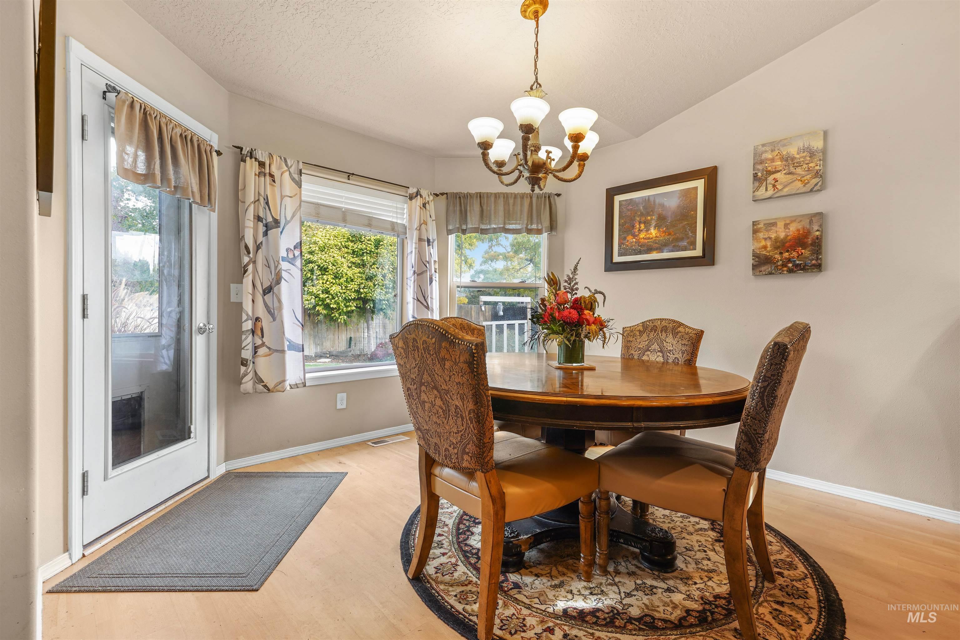 500 East 19th Street Burley, ID 83318 - Photo 5 of 31 Dining space with plenty of natural light, light wood-style floors, a chandelier, vaulted ceiling, and a textured ceiling