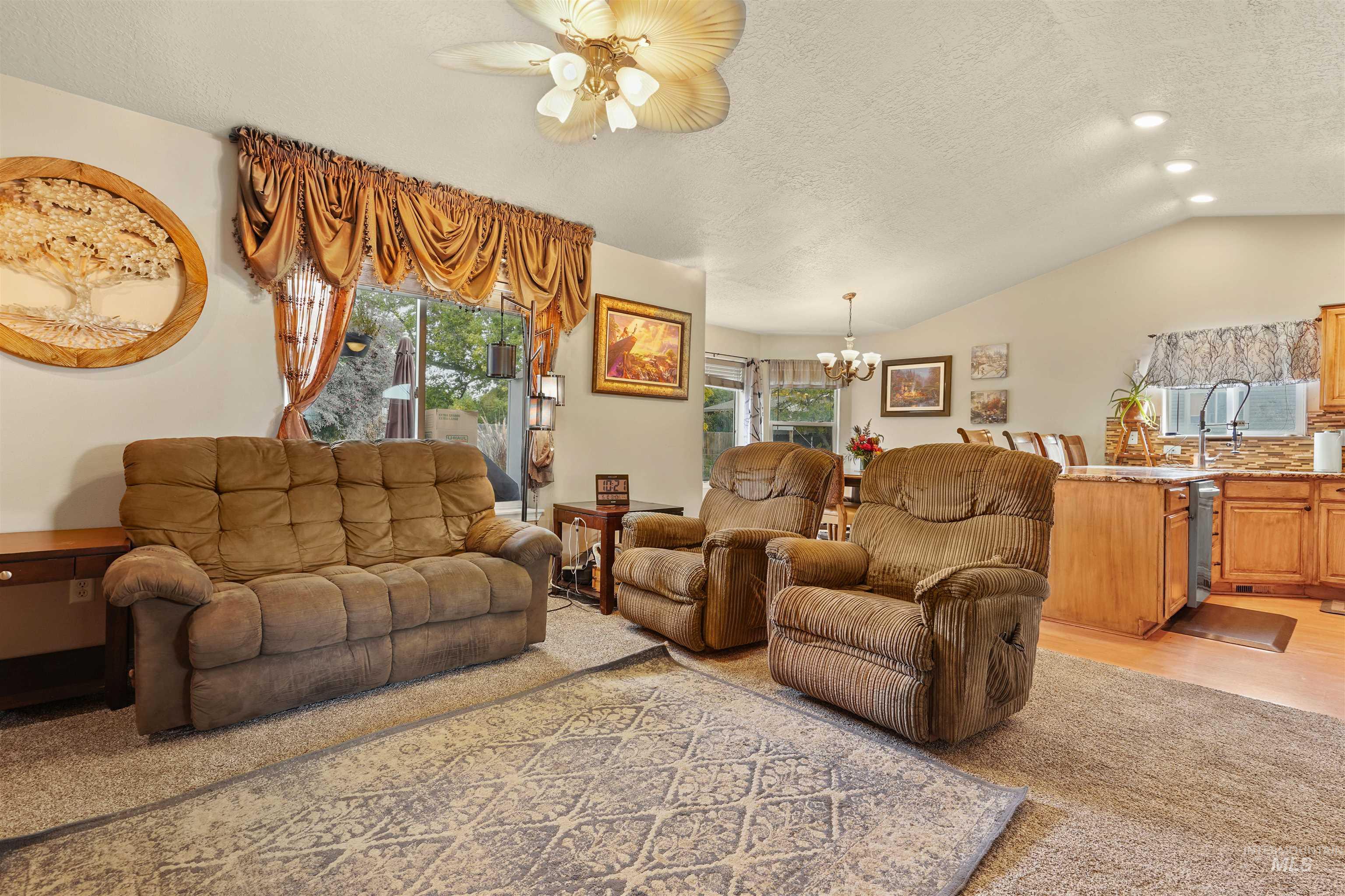 500 East 19th Street Burley, ID 83318 - Photo 7 of 31 Living area with vaulted ceiling, a textured ceiling, a chandelier, light wood-style flooring, and a ceiling fan