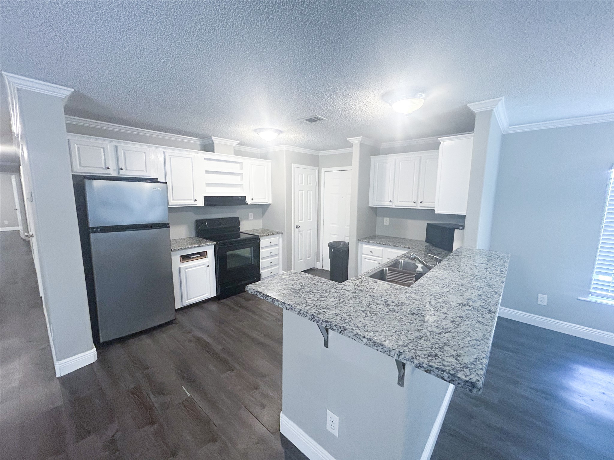 113 Varsity Circle Huntsville, TX 77340 - Photo 4 of 16 a kitchen with granite countertop a refrigerator a sink a stove a microwave and wooden floor