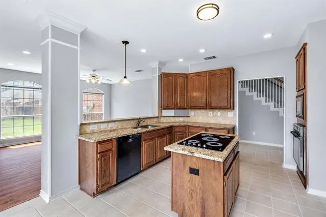 a kitchen with stainless steel appliances granite countertop a stove a sink dishwasher and a refrigerator with wooden floor