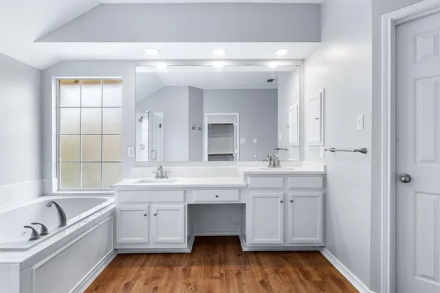 a spacious bathroom with a double vanity sink a mirror and a bathtub