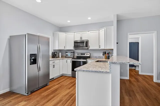 a kitchen with granite countertop a refrigerator stove and wooden floor