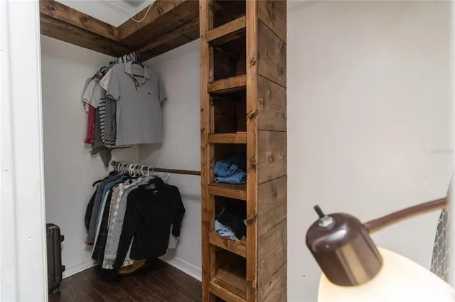 a walk in closet with wooden floor