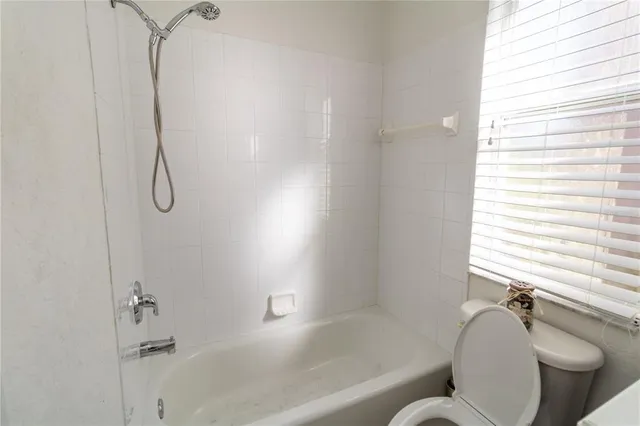 a bathroom with a granite countertop toilet and a bathtub