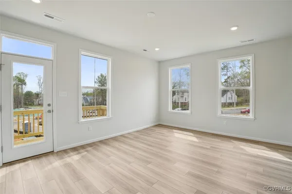 a view of an empty room with a window and wooden floor