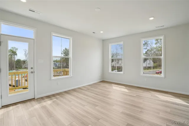 a view of an empty room with a window and wooden floor