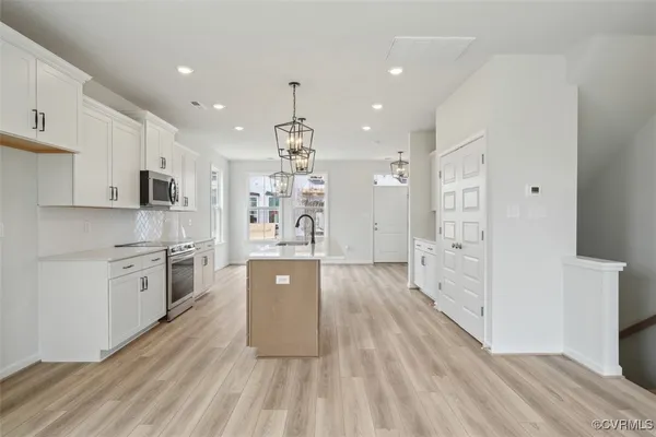 a large kitchen with stainless steel appliances a large counter top a stove a sink dishwasher and a refrigerator with wooden floor