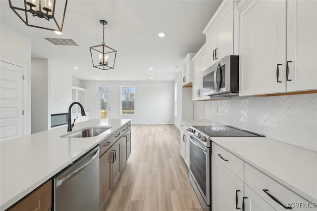 a kitchen with stainless steel appliances granite countertop a sink dishwasher a stove and a microwave oven with cabinets