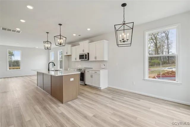 a large kitchen with stainless steel appliances granite countertop a stove a sink dishwasher and a large refrigerator with wooden floor