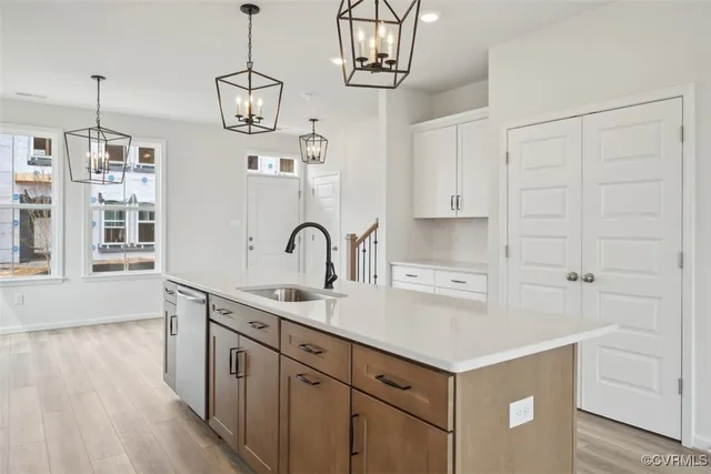 a kitchen with a sink dishwasher a stove and white cabinets with wooden floor