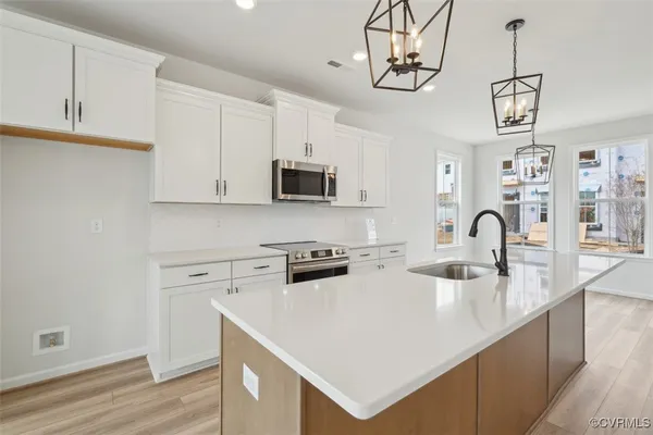 a kitchen with stainless steel appliances granite countertop a stove a sink dishwasher and a microwave with wooden floor