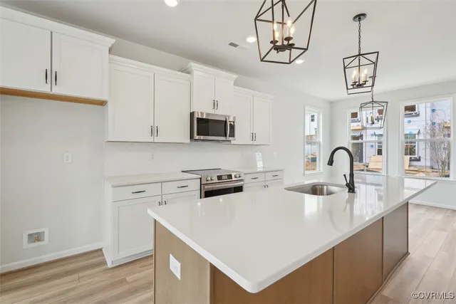 a kitchen with stainless steel appliances granite countertop a stove a sink dishwasher and a microwave with wooden floor
