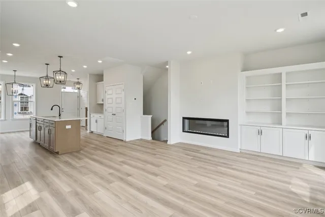 a large white kitchen with wooden floor and a sink